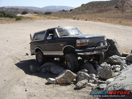 Black Ford Bronco with off-road tires driving over rocks