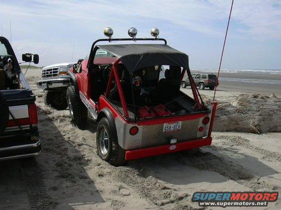 Red off-road vehicle rear view with license plate 458-REH on a beach
