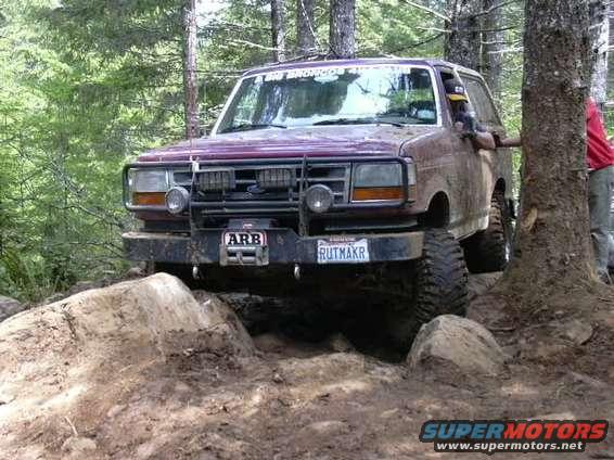 1993 Ford Bronco navigating a difficult rocky trail with large tires and an ARB bumper