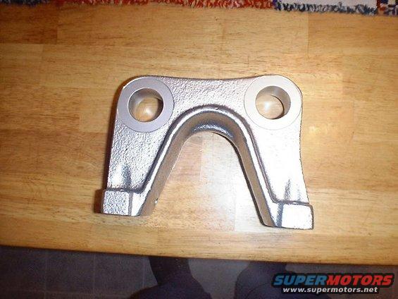 metal suspension part with two circular holes on a wooden surface