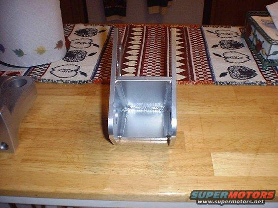 Aluminum suspension component with visible welds, on a wooden table