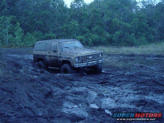 Mud-covered 1980 Ford Bronco stuck in mud, front 3/4 view