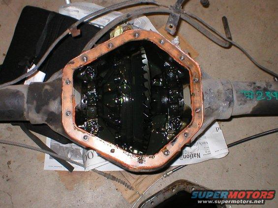 Differential housing with copper gasket removed, showing gears and dark fluid