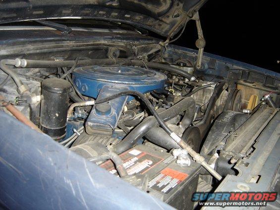 engine bay with blue air cleaner, battery, and fan visible