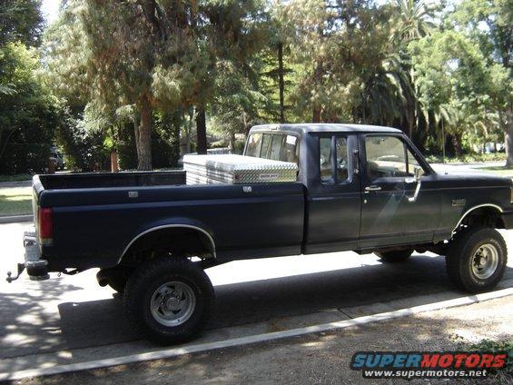 Black Ford F-250 pickup truck, crew cab, long bed, with a toolbox in the bed. Lifted suspension