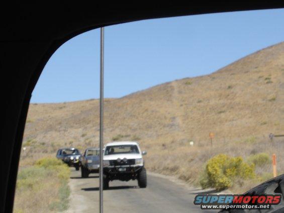 White Ford F-series truck with off-road modifications, front view, driving on a dirt road