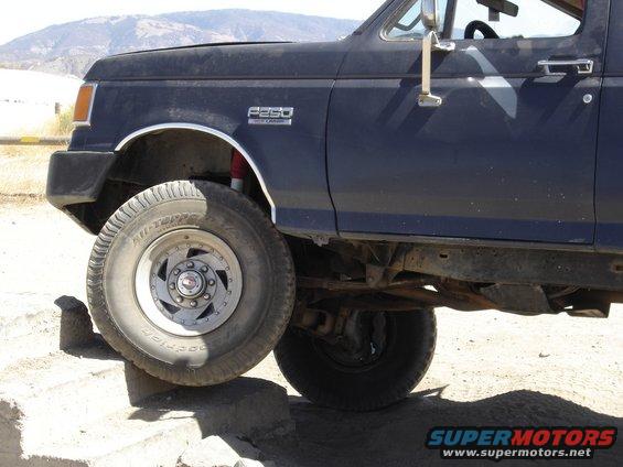 Dark blue Ford F-250 truck, front wheel on rock. Has F-250 badge