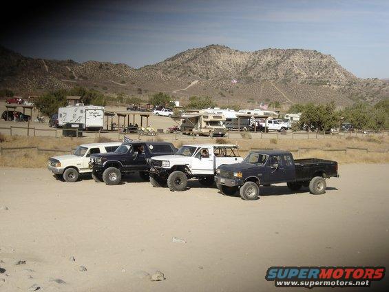 Four-door 1987 Ford F-250 pickup truck parked with other trucks and RVs in a desert area