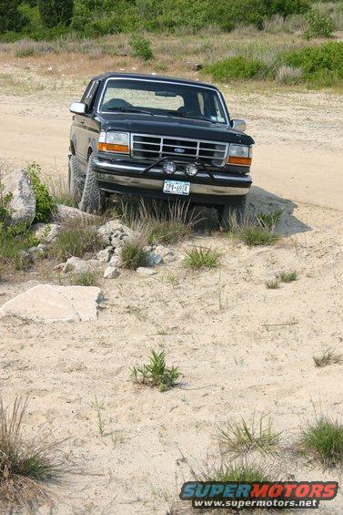 1993 Ford Bronco driving over rocks on a dirt path