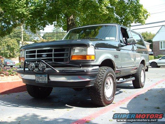 Gray and black Ford Bronco with aftermarket grille guard and off-road tires parked on a street