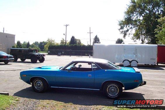 Blue 1970 Plymouth Barracuda parked next to a trailer and a Hummer