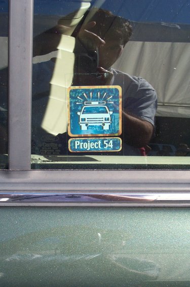 Sticker on car window shows a police car graphic and text 'Project 54'