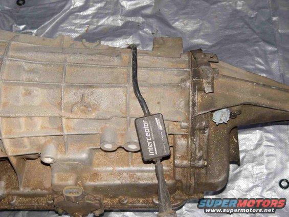 Transmission housing with 'Interceptor' module attached. Watermark reads SUPERMOTORS.NET