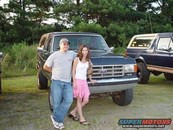 Couple in front of dark blue Ford Bronco, another Bronco visible to the right