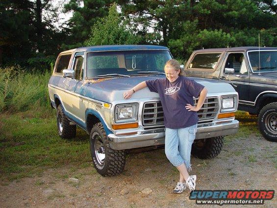 Blue and silver 1978 Ford Bronco with a woman leaning on its hood