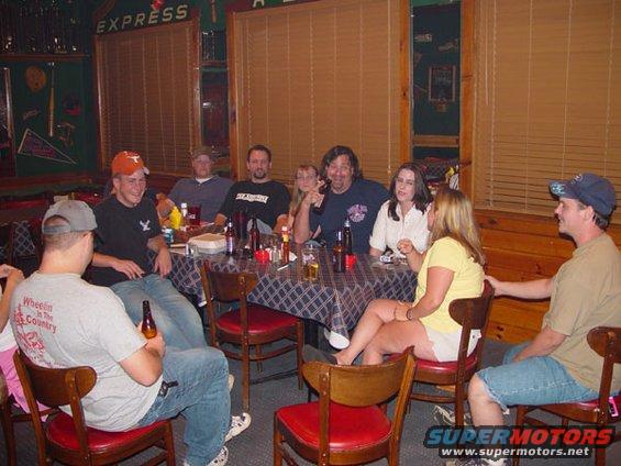 People gathered around a table with drinks and food in a casual setting