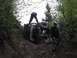 1993 Ford Bronco - An off-road vehicle is stuck on a steep, wooded trail with several people attempting to help.