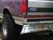 1993 Ford Bronco - Rear view of a maroon and tan Ford Bronco with off-road tires and a chrome bumper, showing signs of wear and tear.