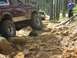 1993 Ford Bronco - Two Ford Broncos navigate a challenging rocky off-road trail through a forest.