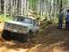 1993 Ford Bronco - This lifted SUV is tackling a challenging off-road trail with steep inclines and rocky terrain.