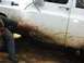 1993 Ford Bronco - A person cleans mud from the side of a white SUV after off-roading.