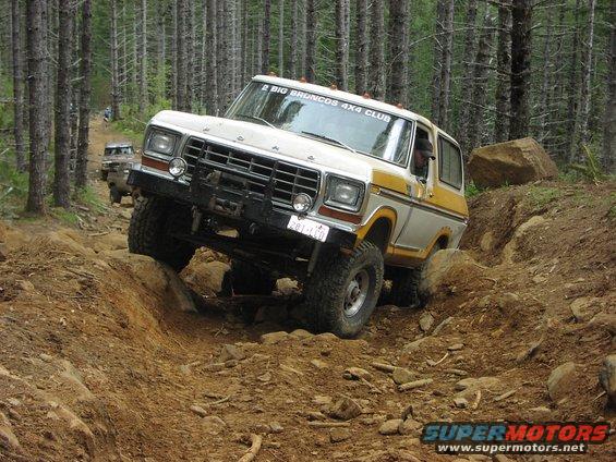 1978 Ford Bronco climbing a rocky trail, with another Bronco behind it. "2 BIG BRONCOS 4X4 CLUB" sticker on windshield