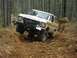 1993 Ford Bronco - Two Ford Broncos navigate a challenging off-road trail through a forest.