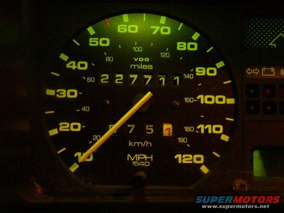 Car dashboard with illuminated speedometer showing 227771 miles and 75 km/h, with a yellow needle