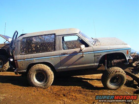 Mud-covered gray 1984 Ford Bronco II side view, lifted suspension, off-road tires