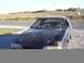 1988 Ford Mustang - A black Ford Mustang sits in a gravel lot with a field in the background.