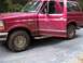 1994 Ford Bronco - A red 1994 Ford Bronco is shown with both driver's side doors ajar, parked on a gravel surface.