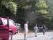 1994 Ford Bronco - Two Ford Bronco SUVs are parked on a dirt road in a wooded area with several people standing around.