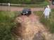 1994 Ford Bronco - A dark gray Ford Bronco drives on a challenging dirt trail with people watching.
