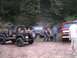 1994 Ford Bronco - Three off-road vehicles are parked on a dirt path in a wooded area.