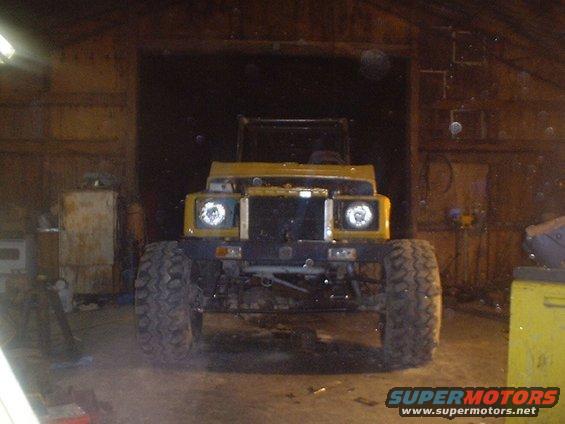 Yellow off-road vehicle with large tires parked inside a garage
