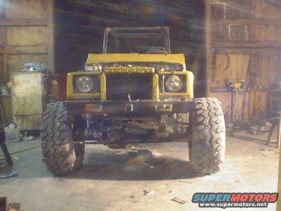 Yellow Suzuki Samurai with large tires in a garage