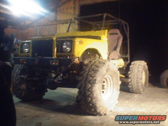 Yellow off-road vehicle with large tires and a roll cage, viewed from the front