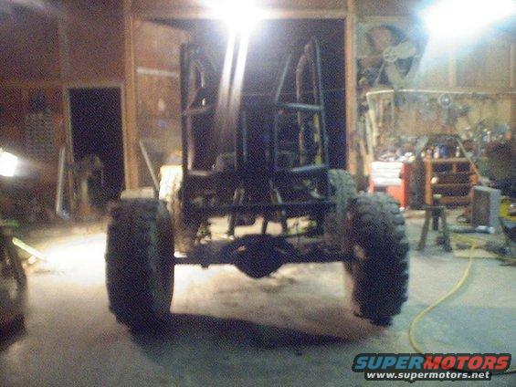 Off-road buggy frame with large tires and roll cage, in a garage