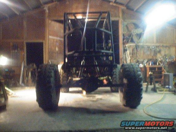Roll cage frame of a custom buggy with large tires, in a garage