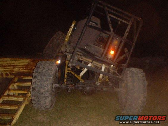 Off-road vehicle with roll cage on a trailer ramp at night