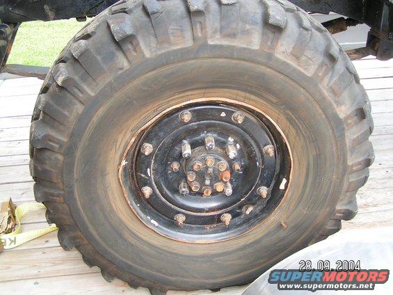 Close-up of a large off-road tire and black wheel with multiple lug nuts