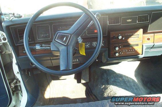 Car interior with blue steering wheel, wood-grain dashboard, and cassette player