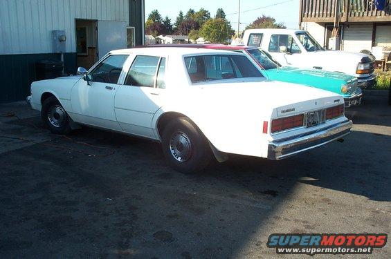 White sedan parked next to a turquoise car and a white pickup truck