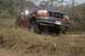 1994 Ford Bronco - A red Ford truck is partially submerged in dry grass and brush, seen from the front-right.