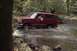1994 Ford Bronco - A red 1994 Ford Bronco navigates a shallow stream surrounded by trees.