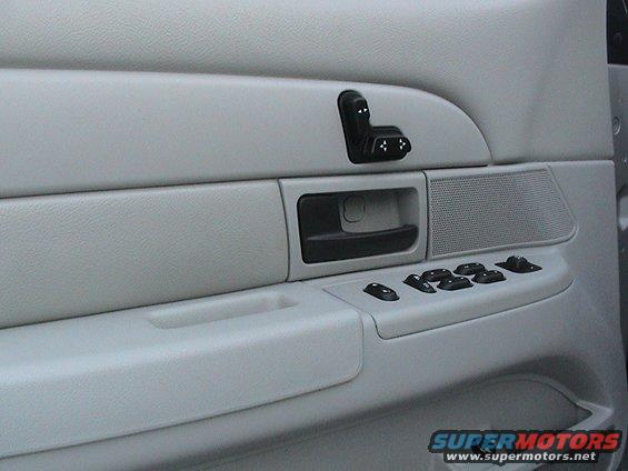 Light gray car interior door panel with power window and seat controls