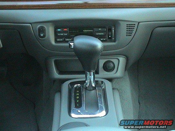 Car's center console with automatic shifter, climate controls, and a power outlet