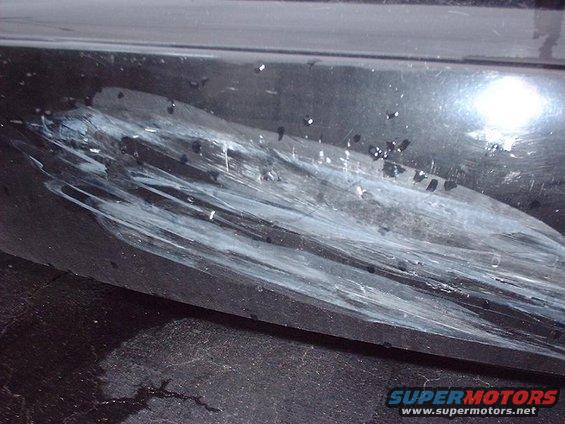 Close-up of a black car bumper with white paint transfer and deep scratches