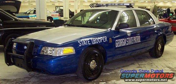 Blue and silver 2001 Ford Crown Victoria police car with a push bumper and light bar