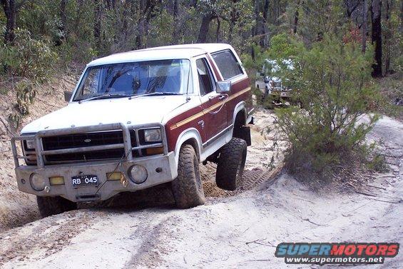 White and maroon Ford Bronco with a brush guard on a dirt track
